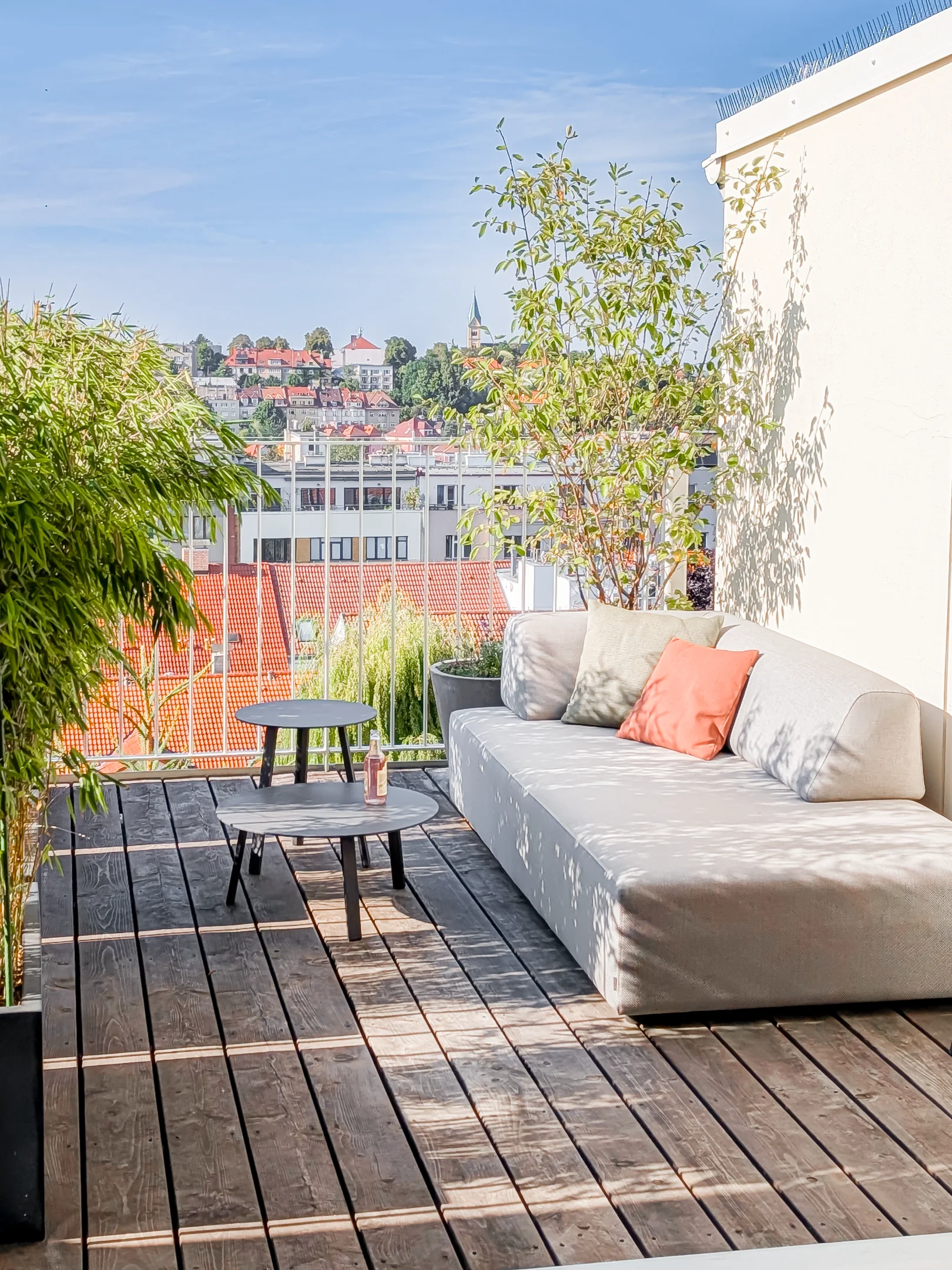 Moderní terasa s posezením, stolek a výhled na město.